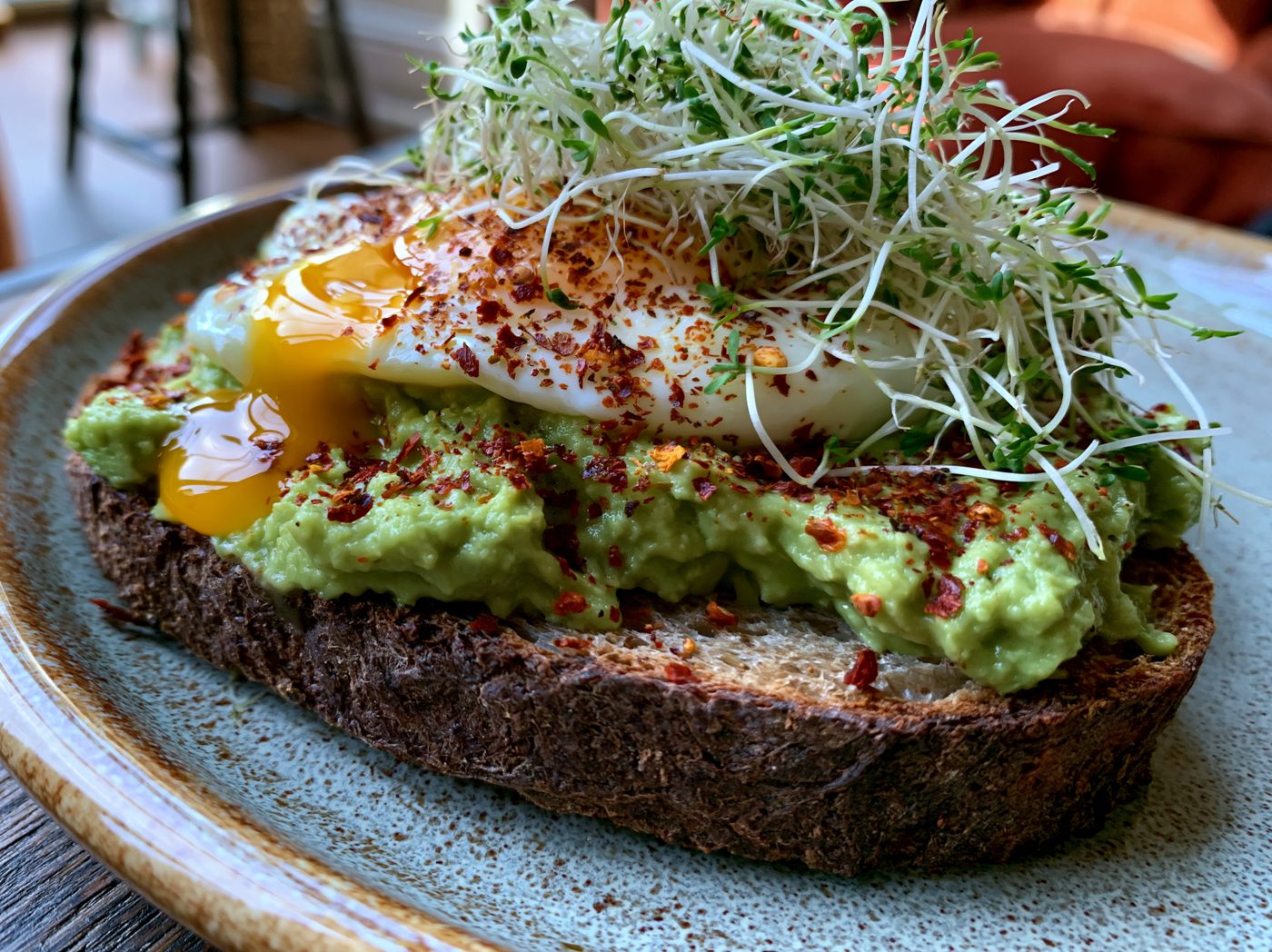Fertiger Avocado-Toast mit Ei, Sprossen und Chiliflocken